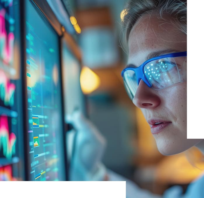 Analyst in safety glasses studying campaign data on screens