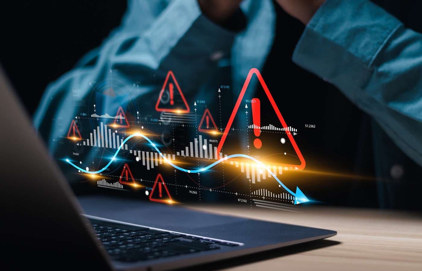 Red warning triangles over a laptop in a dark scene